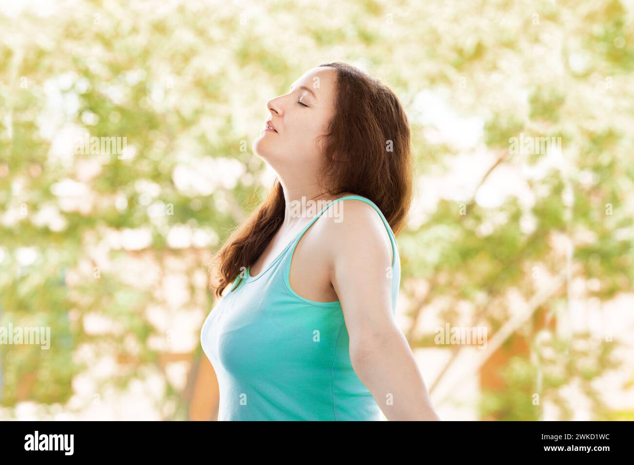 Ritratto laterale di una donna che respira aria fresca all'aperto in estate con gli alberi sfondo Foto Stock