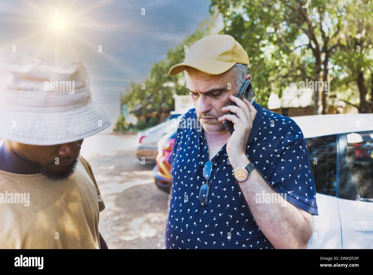 vecchio caucasico che parla al telefono con un giovane africano nel parcheggio Foto Stock