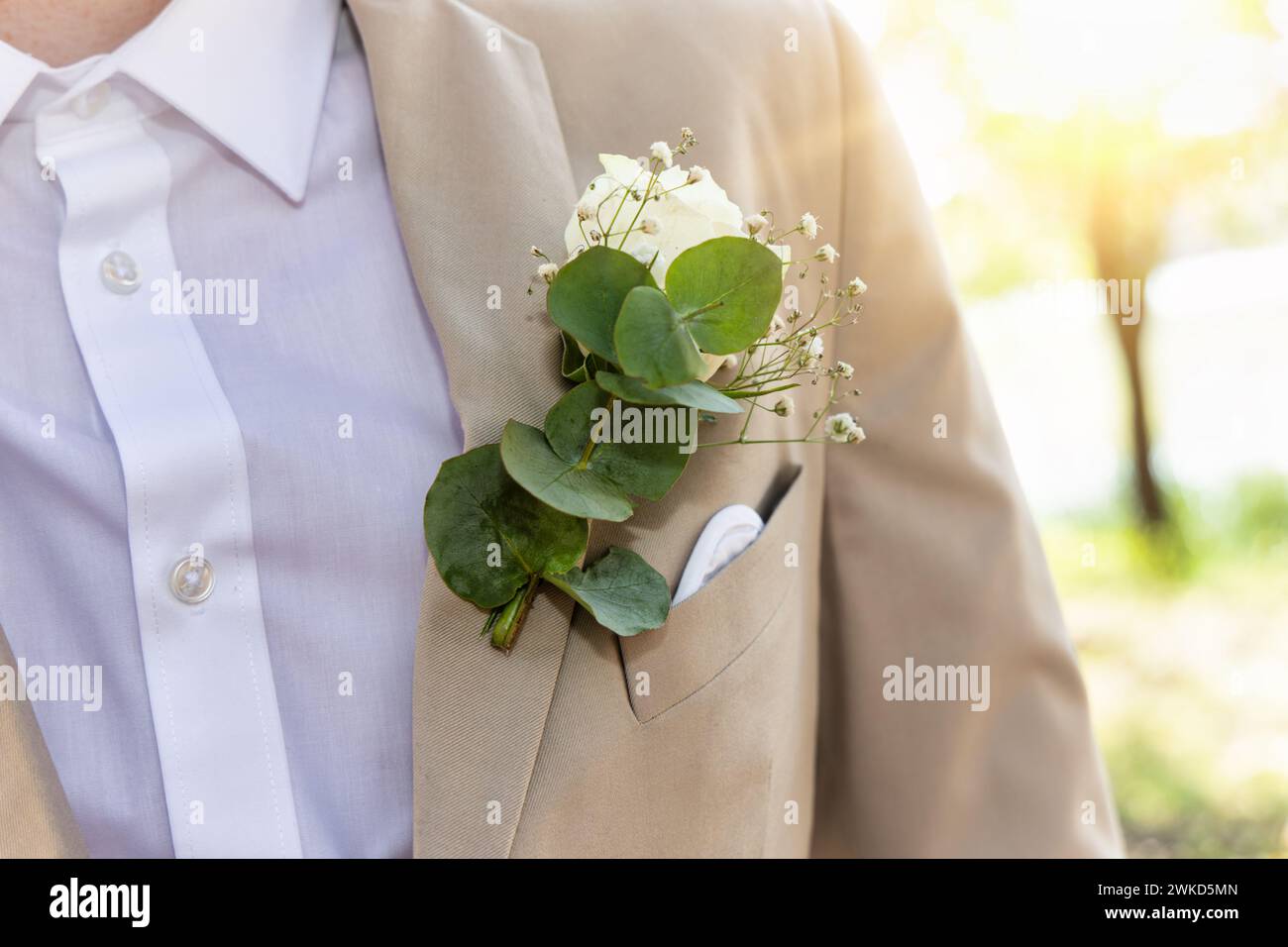 fiore fissato alla tuta da sposo, all'aperto al tramonto Foto Stock