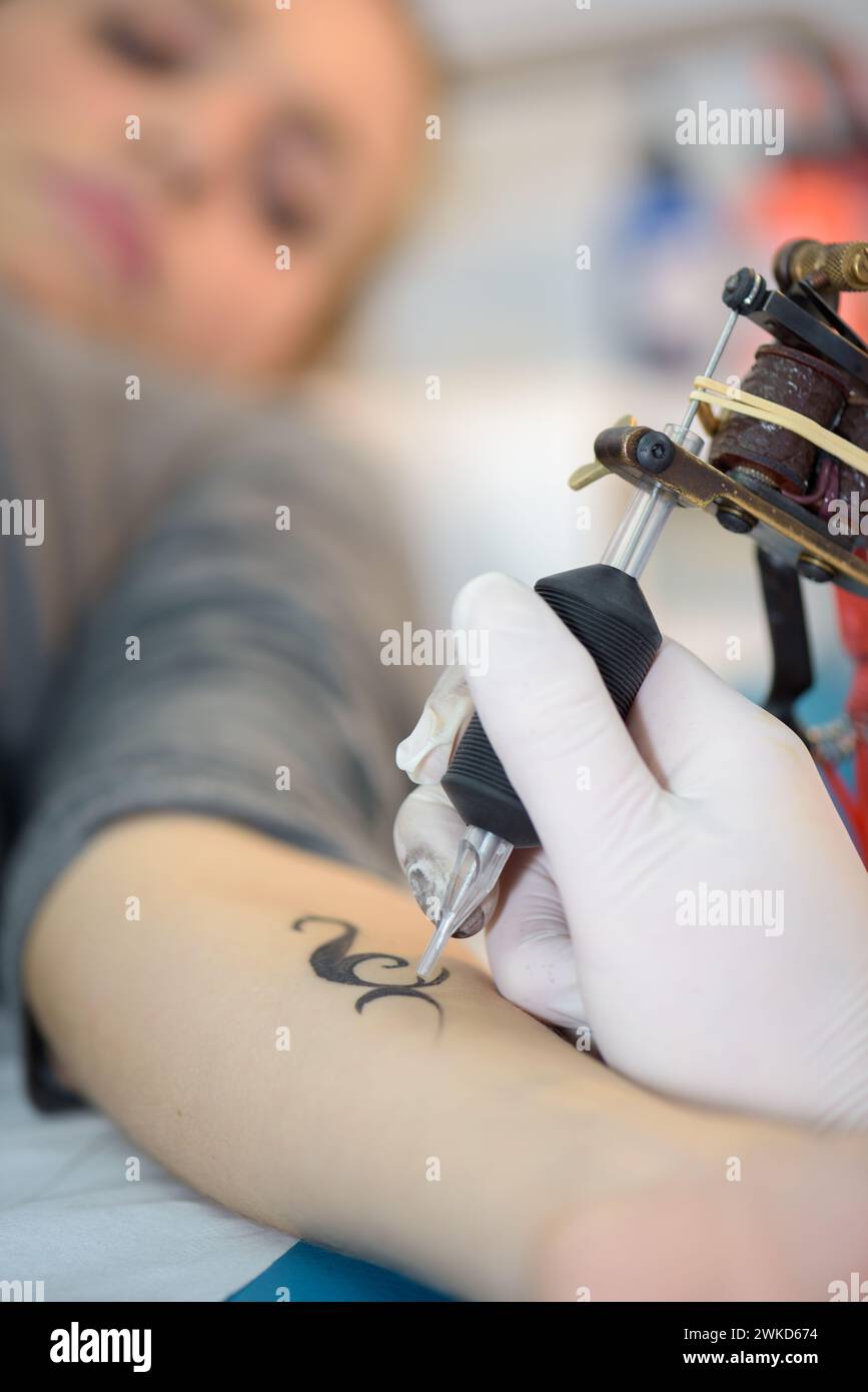 un braccio femminile che viene tatuato Foto Stock