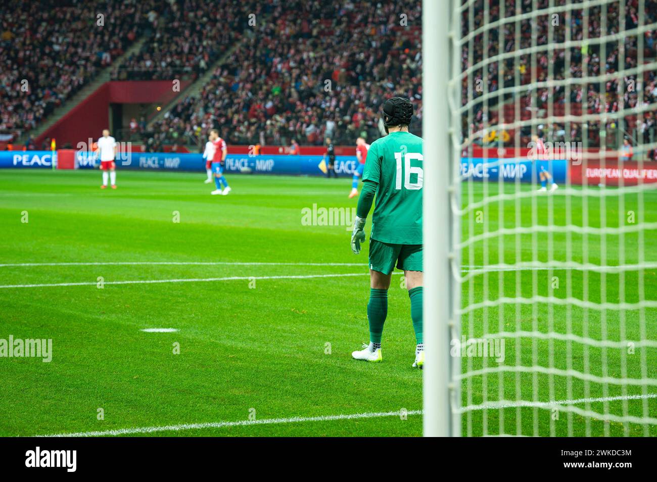 Palo per la porta di calcio e partita di calcio sullo sfondo. I cartelli a LED riportano l'ISCRIZIONE PACE in inglese e ucraino ar russo. Foto Stock
