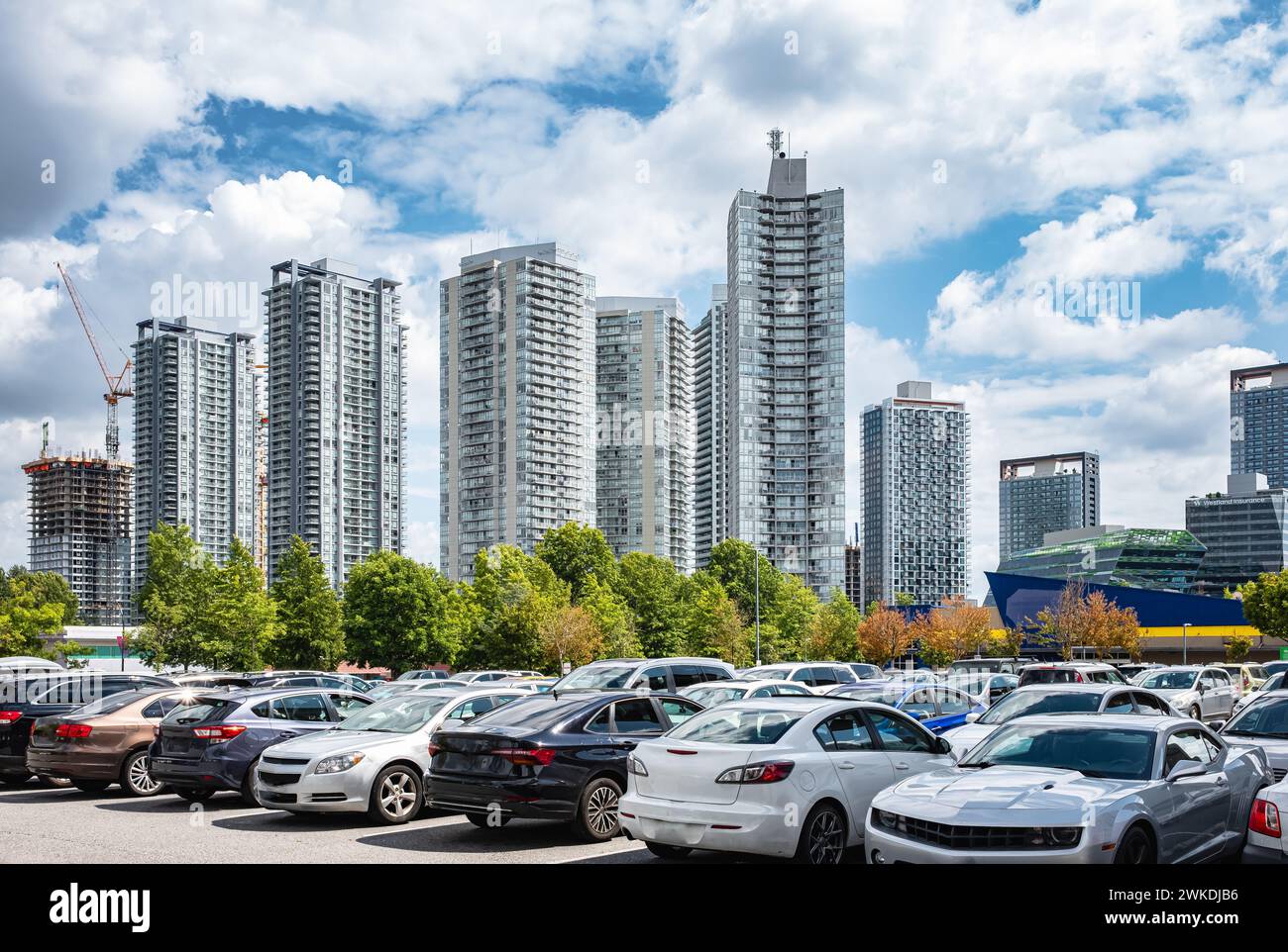 Vita di città. Auto parcheggiate di fila in un parcheggio all'aperto a Vancouver, British Columbia, Canada. Alti edifici sullo sfondo. Parcheggio auto in ampio parcheggio asfaltato l Foto Stock