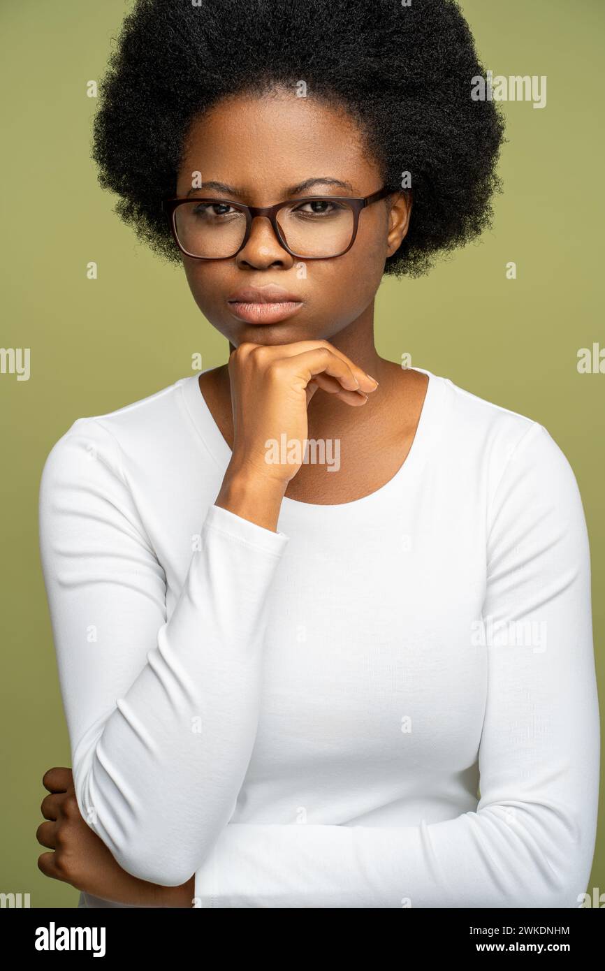 Donna afroamericana intelligente e sicura di sé con occhiali che guardano la fotocamera con uno sguardo rigoroso. Foto Stock