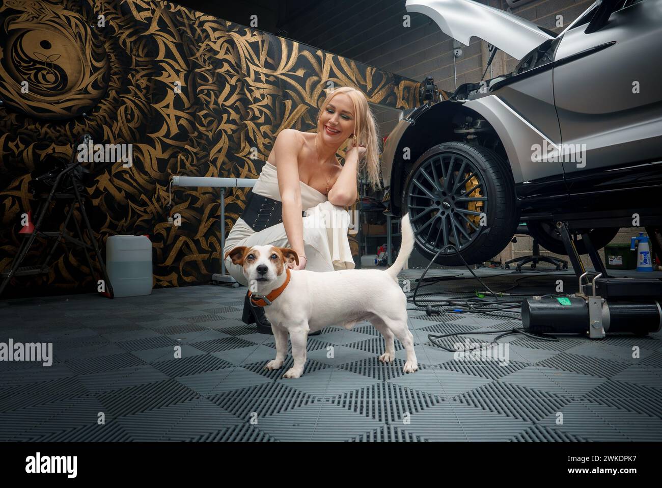 Bionda Lady accompagnata dal suo cane presso l'esclusivo servizio Auto Service Facility Foto Stock