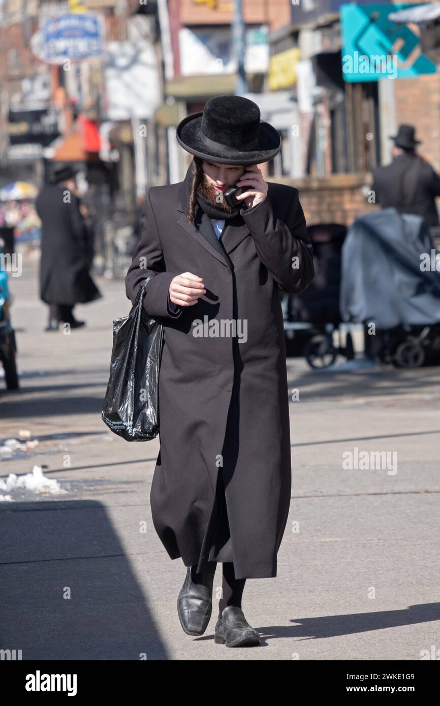 Un ebreo chassidico cammina su Lee Ave. Mentre parla al suo telefono. A Williamsburtg, Brooklyn, New York. Foto Stock