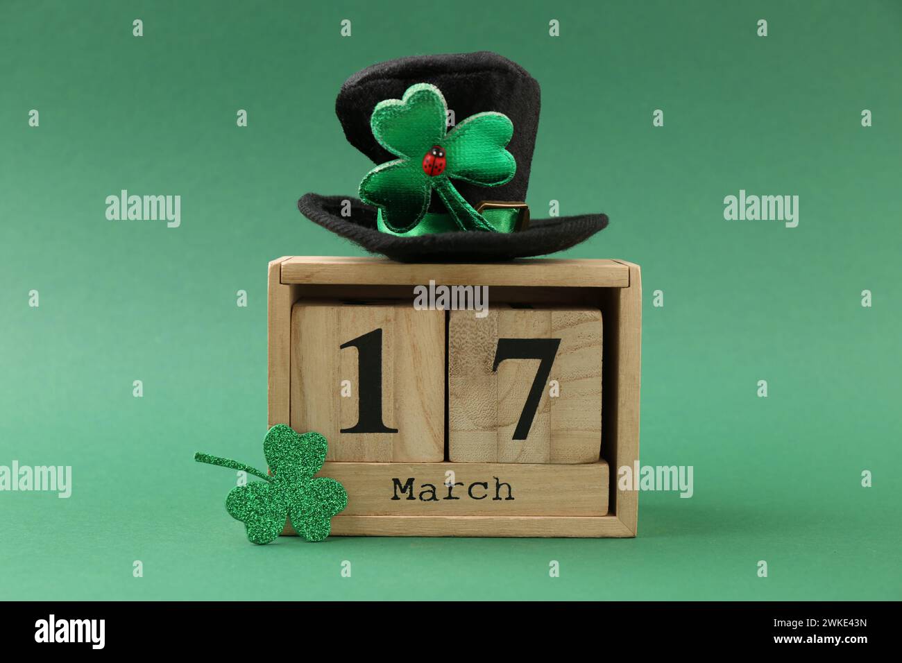 St Giorno di Patrick - 17 marzo. Calendario a blocchi, cappello di leprechaun e foglia di trifoglio decorativo su sfondo verde Foto Stock
