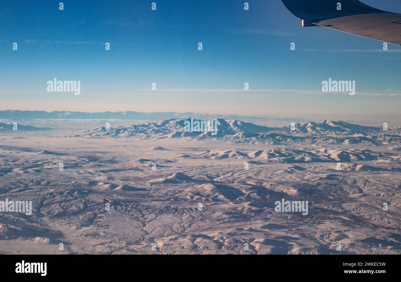 Il cielo con le nuvole e le montagne nella neve. Foto scattata da un aereo. Ala di un aereo nel cielo. Foto Stock