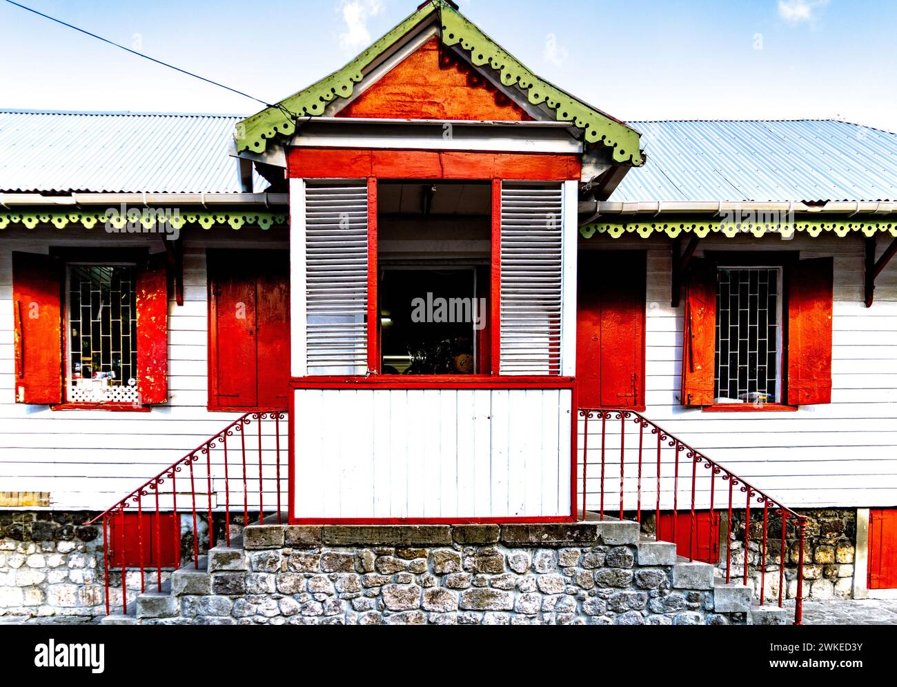 Una casa in legno con cornici rosse e tetto verde a Dominica Foto Stock