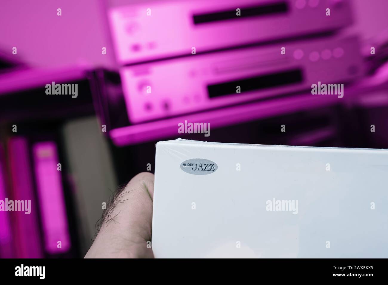 Cartellonistica jazz ad alta definizione che adorna il pacchetto di un nuovo SACD, con un sistema audiofilo hi-fi sfocato sullo sfondo su sfondo magenta, promettendo un'esperienza musicale coinvolgente. Foto Stock