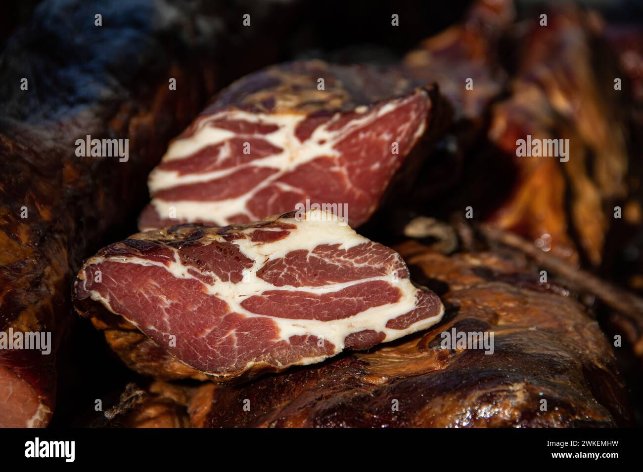 Deliziosi pezzi di carne affumicata esposti per la vendita nel mercato presentato per la vendita in un mercato agricolo nel villaggio di Kacarevo, pancetta gastro e carne secca Foto Stock