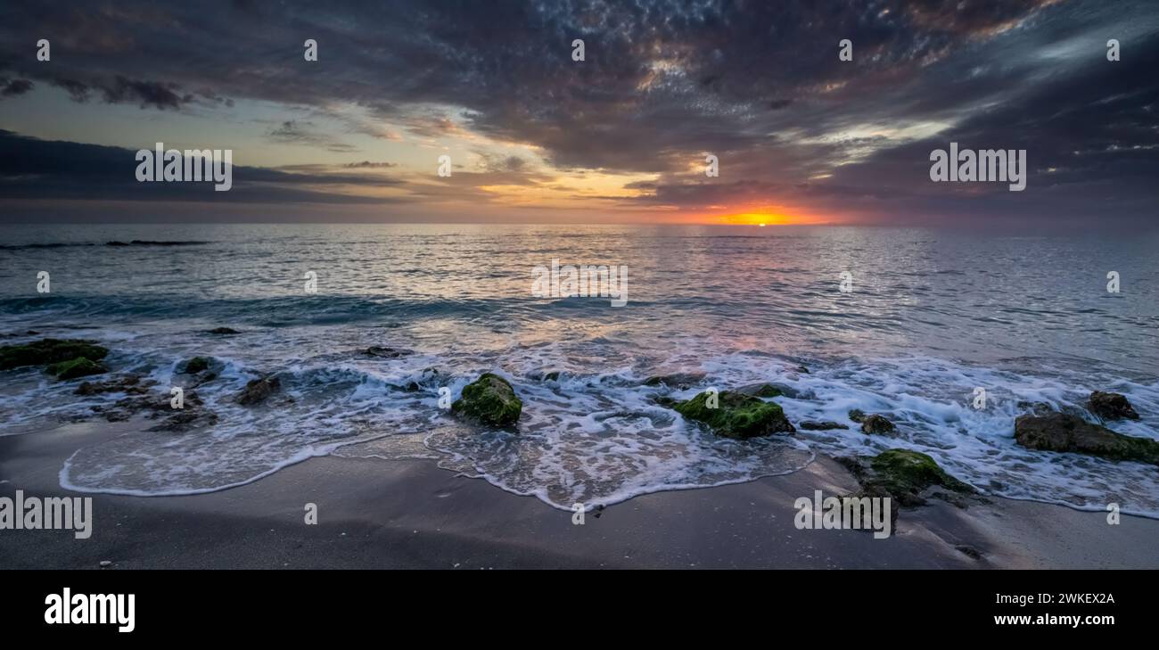 Sole all'orizzonte che si infrangono attraverso nuvole scure sul Golfo del Messico a Caspersen Beach a Venice, Florida Foto Stock