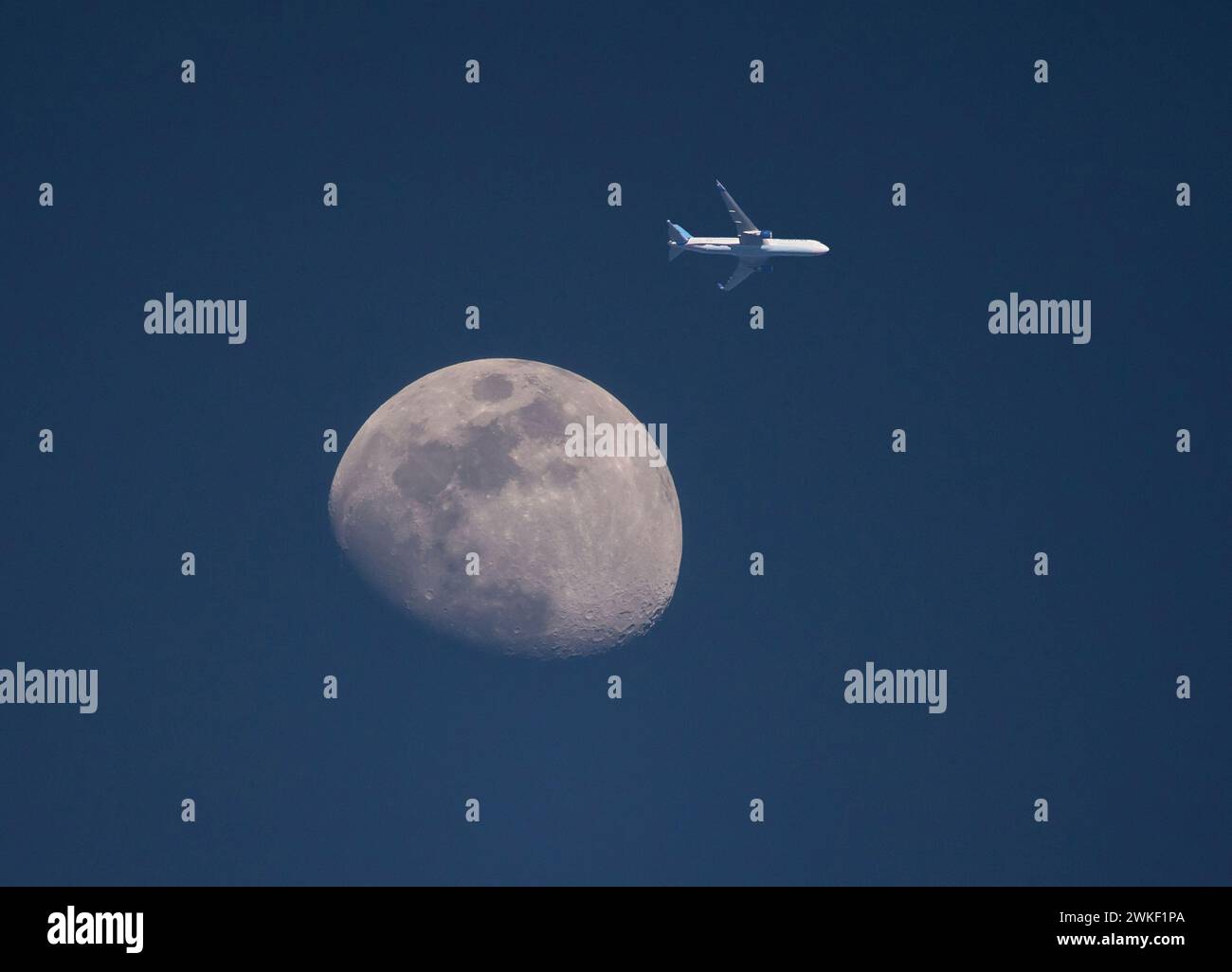 Un aereo di linea commerciale passa accanto alla luna a bassa quota al tramonto. Foto Stock