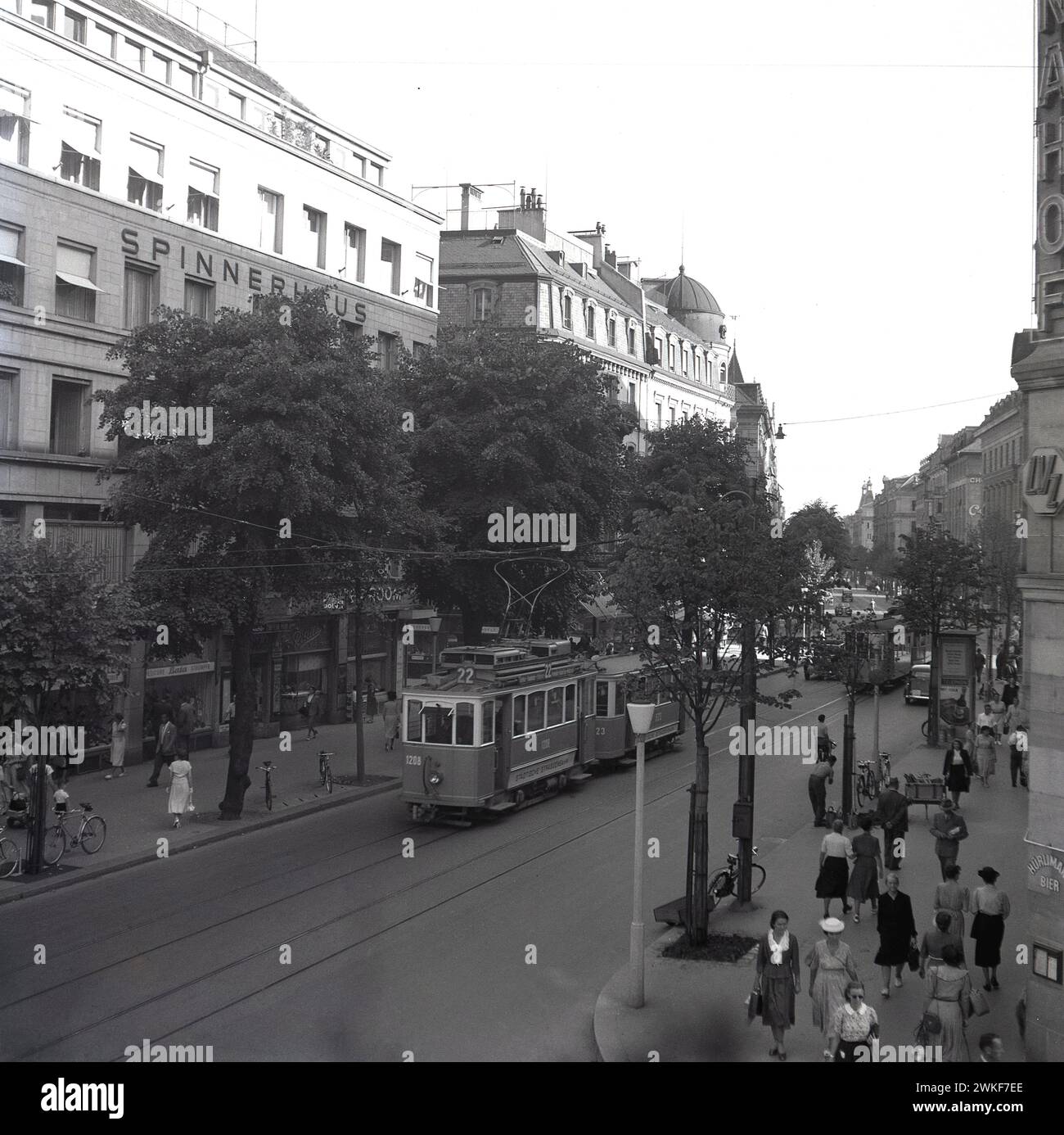 Anni '1960, storica scena di strada, che mostra persone e un tram sulla Bahnhofstrasse alberata a Zurigo, Svizzera. Visto nella foto, l'edificio Spinnerhaus. Situata in centro, la strada risale al 1864 ed è un importante collegamento nella rete tranviaria di Zurigo. Foto Stock