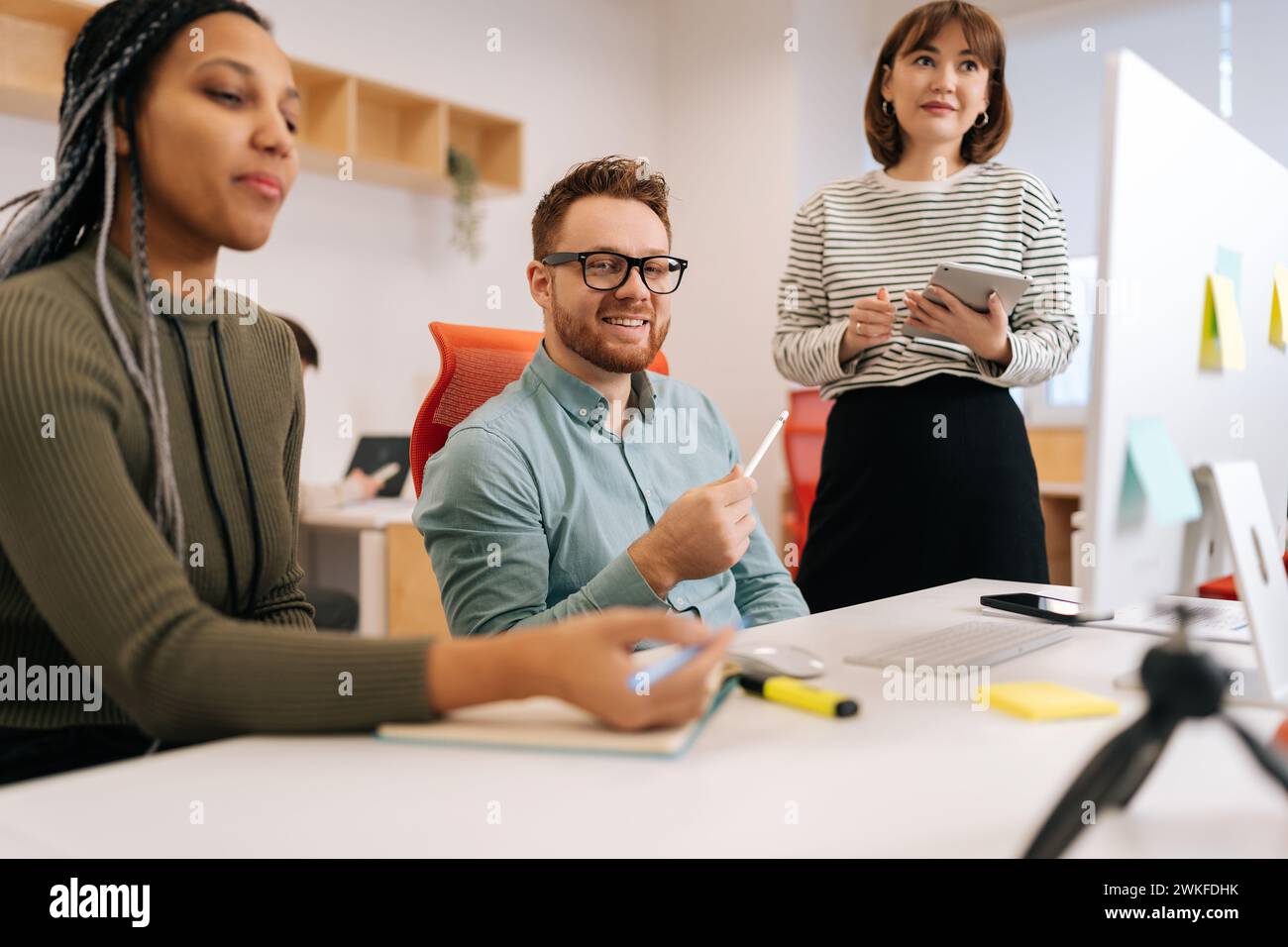 Colleghi multietnici felici dipendenti che collaborano in ufficio parlano lavorando insieme sul posto di lavoro. Collaboratori di team di giovani startup diverse Foto Stock