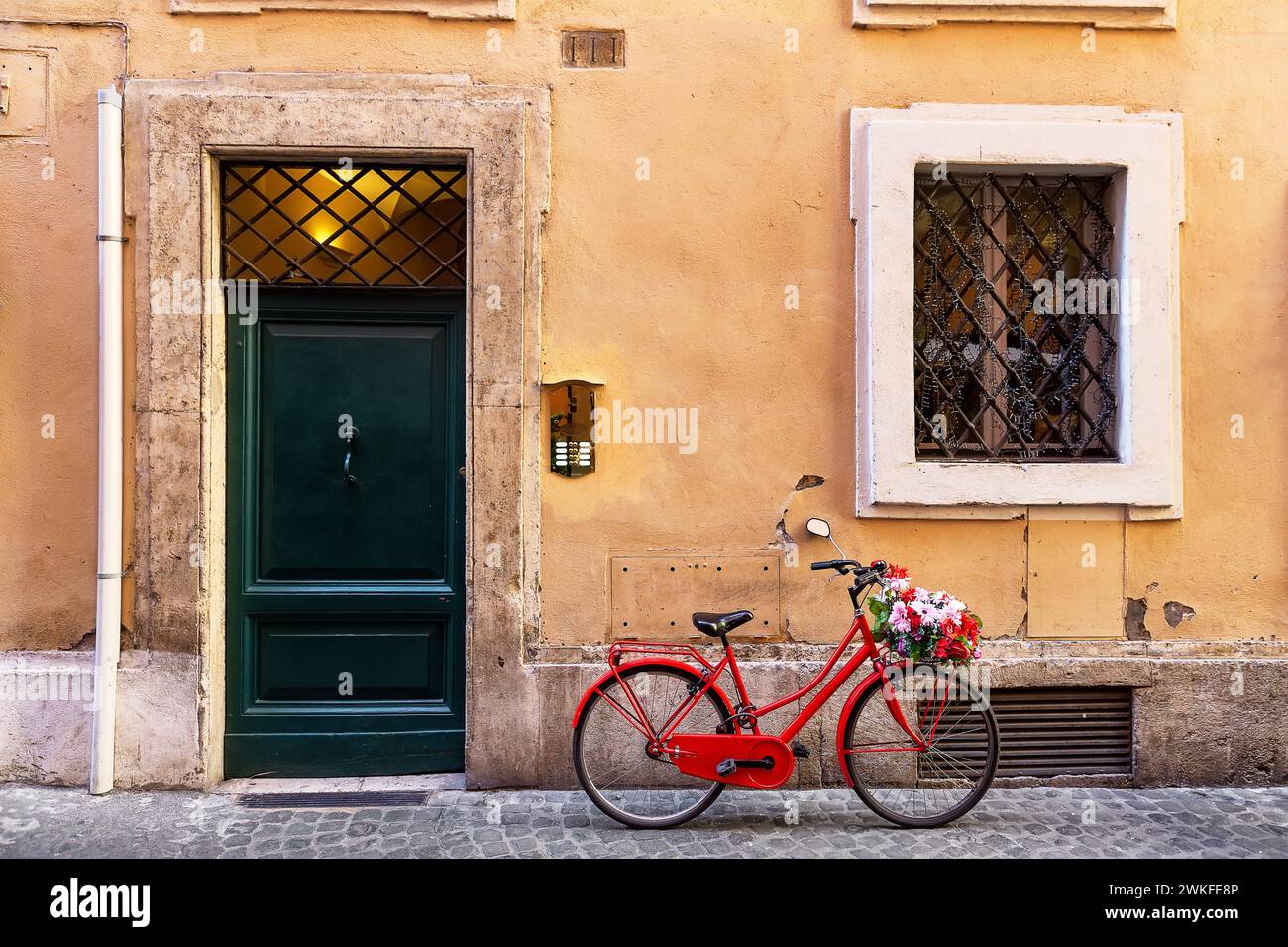 Immagine di una bicicletta rossa in una vecchia e stretta strada acciottolata a Roma, Italia. La vecchia strada di Roma, Italia. Architettura e punto di riferimento di Roma. Foto Stock