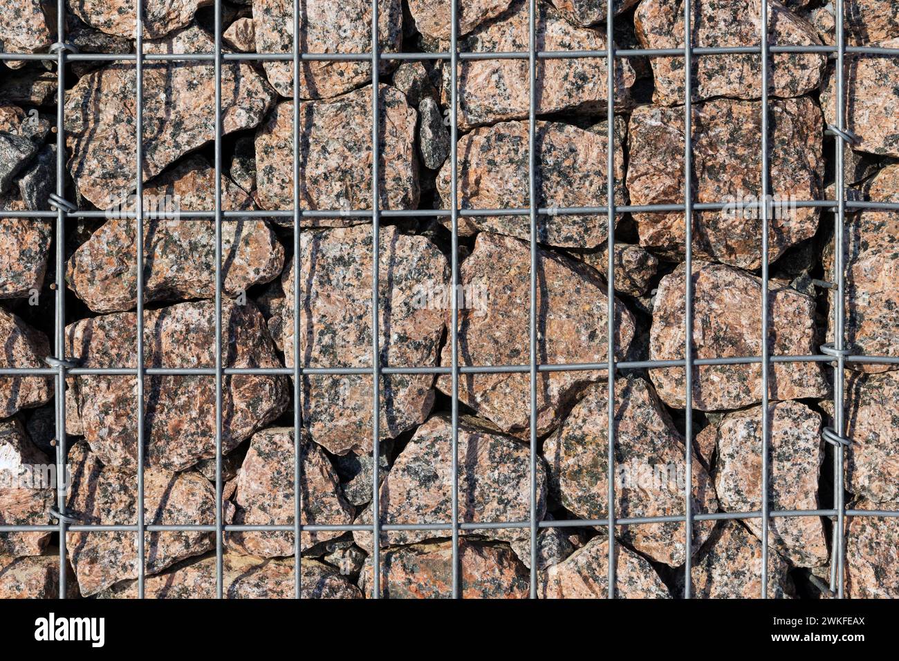 Foto ravvicinata della parete del gabbione, gabbie d'acciaio piene di rocce di granito Foto Stock