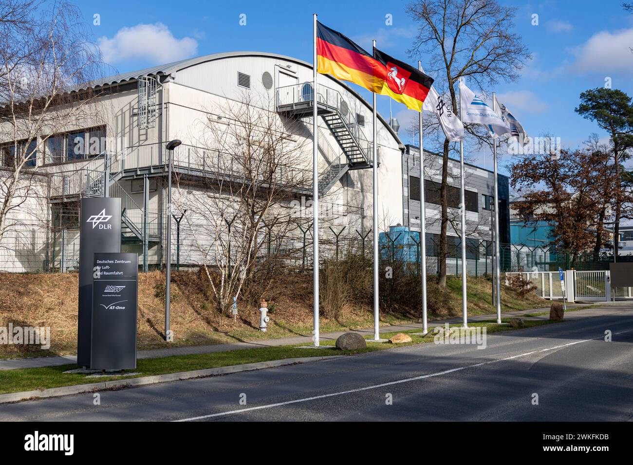 Forschungsflughafen Braunschweig Einfahrt zum Deutschen Zentrum für Luft- und Raumfahrt am Flughafen Braunschweig-Wolfsburg. Auch ist die firma German-Dutch Wind Tunnels e AT-One dort ansässig. Die Fahnenmasten sind bestück mit der Deutschlandfahne, der Fahne für Niedersachen, sowie den ansässigen Unternehmen. Braunschweig Wabe-Schunter-Beberbach Niedersachsen Deutschland *** Braunschweig Research Airport ingresso al German Aerospace Center presso l'aeroporto Braunschweig Wolfsburg la compagnia German Dutch Wind Tunnels e IN una di esse hanno sede anche i flagelli sono decorati con la f tedesca Foto Stock