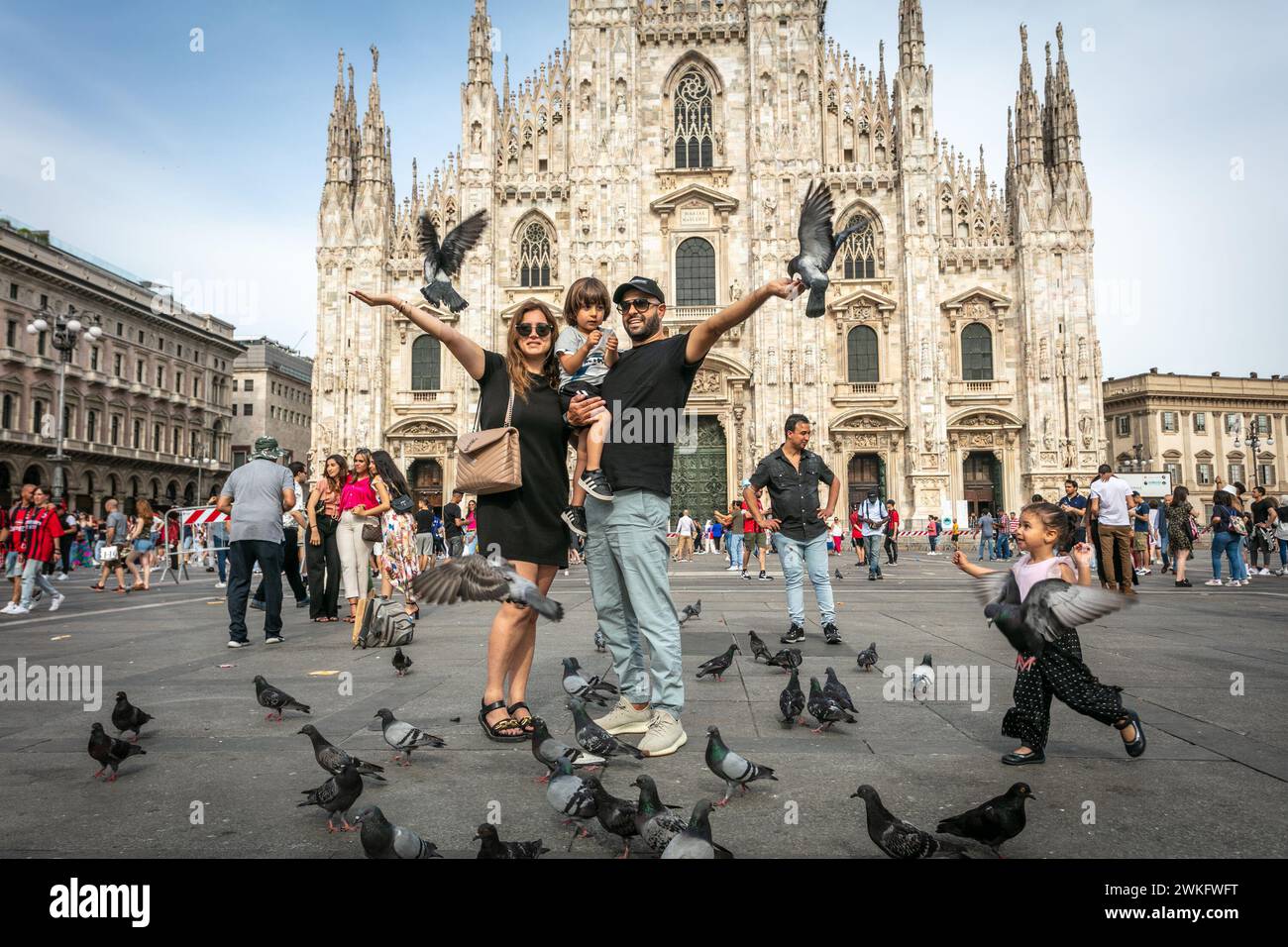 I turisti vengono fotografati nella piazza del Duomo di Milano tra piccioni. Italia. Foto Stock