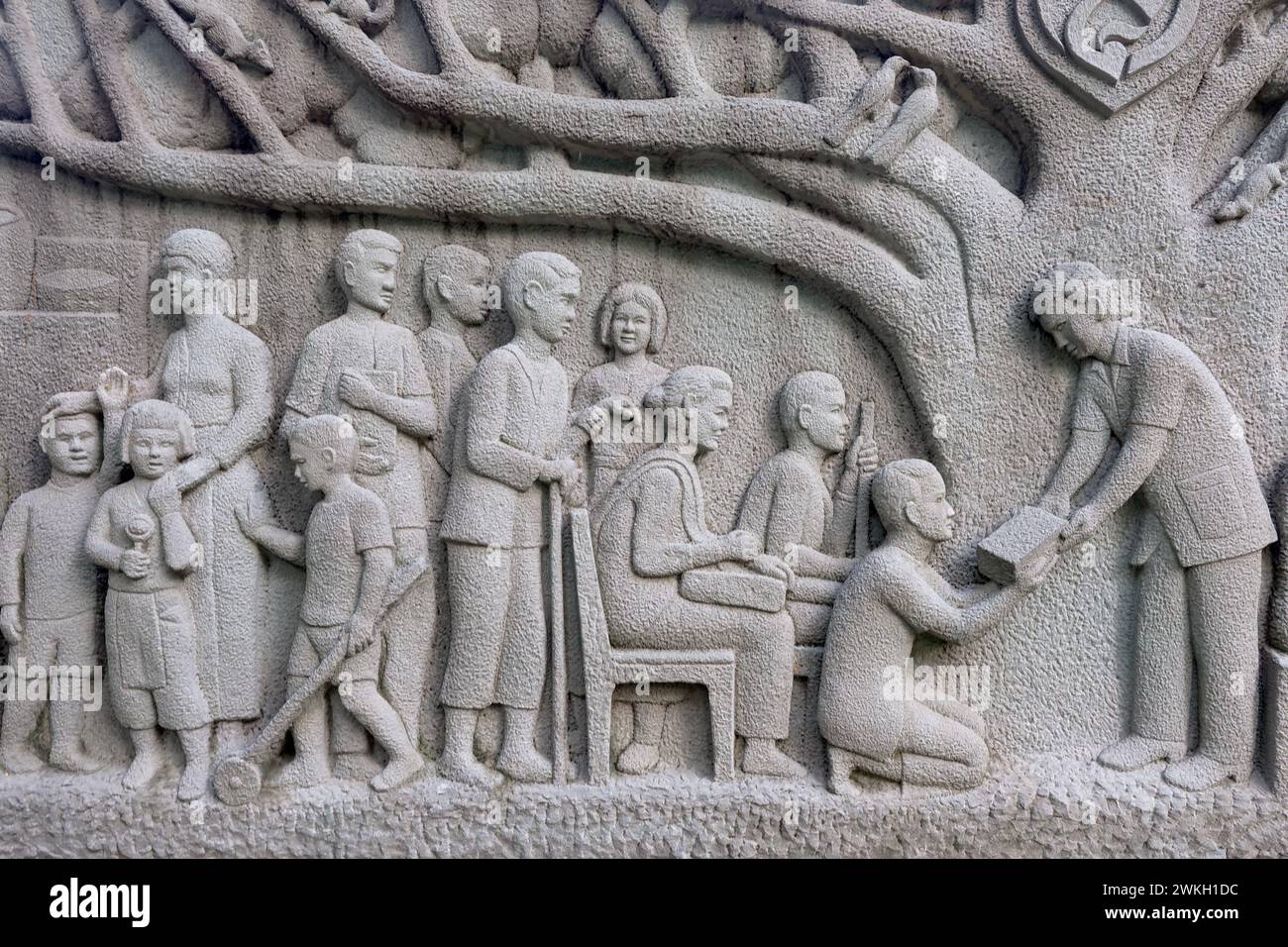 Un fregio nel Somdet Queen Mother Park a Bangkok, Thailandia, raffigurante un funzionario governativo che distribuisce assistenza agli abitanti del villaggio thailandese Foto Stock