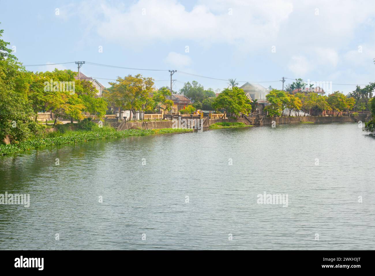 Serena vista sul fiume con villaggio e vegetazione lussureggiante in una giornata di sole nella città di Hue, Vietnam Foto Stock