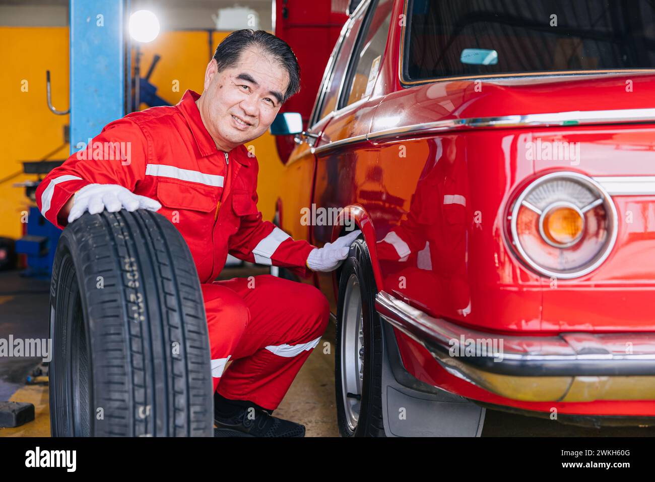Senior professionista asiatico maschio meccanico officina lavoratore felice lavoro ruote pneumatici sostituzione servizio di manutenzione pneumatici auto Foto Stock