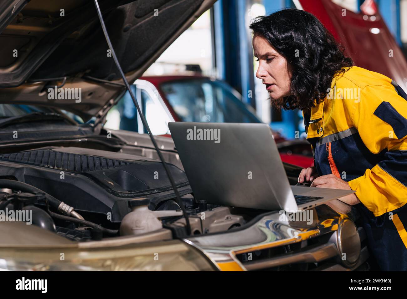 Ingegnere meccanico auto che utilizza computer portatile sintonizzazione ECU analisi diagnosi monitor problema motore in garage auto service Foto Stock