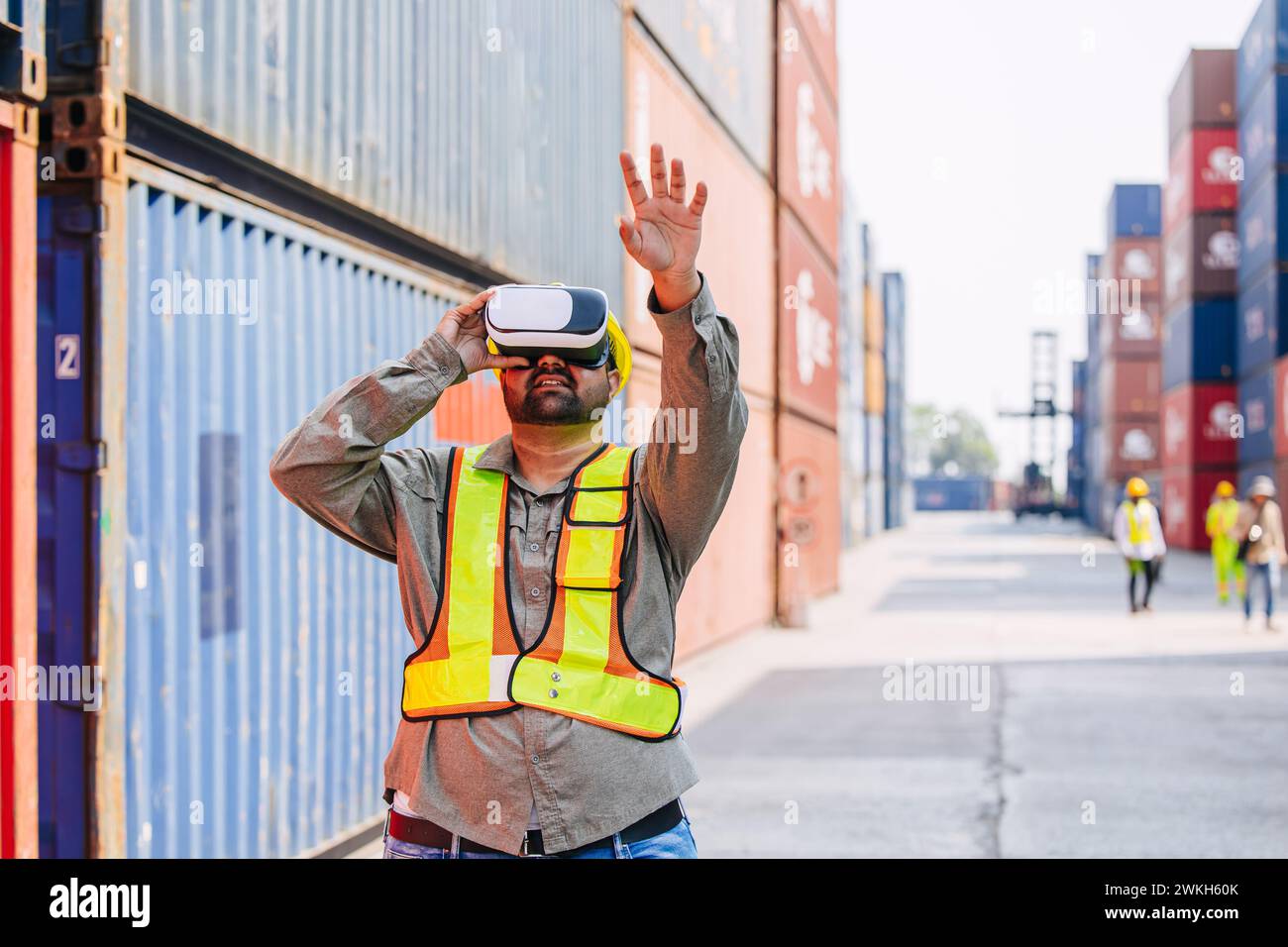 I lavoratori che utilizzano dispositivi con cuffie e auricolari VR Vision Pro Technology lavorano presso Container Yard Construction Site innovazione nel settore della logistica Foto Stock