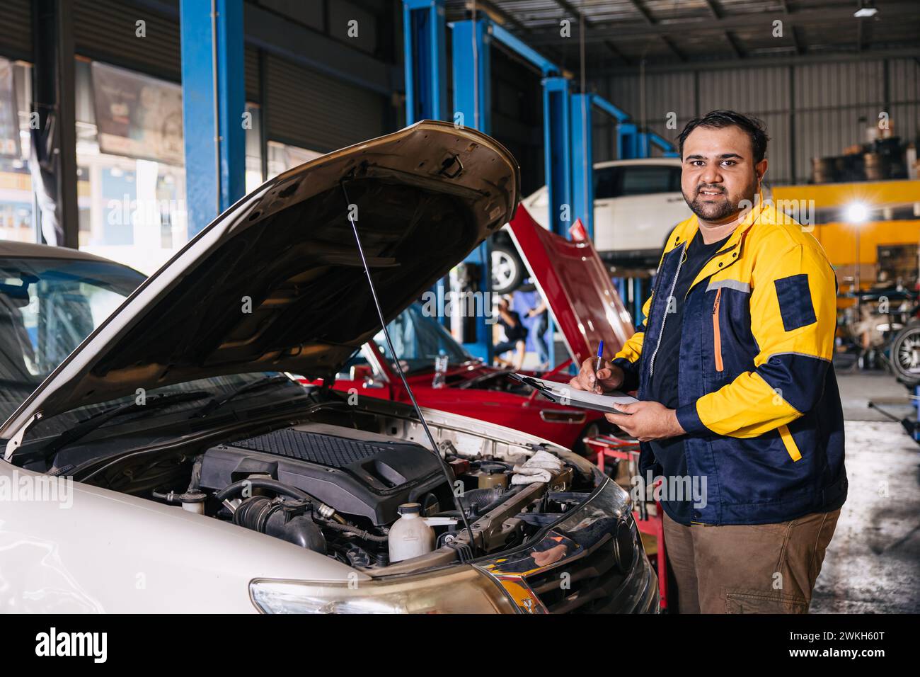 Ritrattista meccanico di auto garage che lavora controllando il motore di auto nel centro di assistenza auto, lavoro maschile professionale indiano Foto Stock