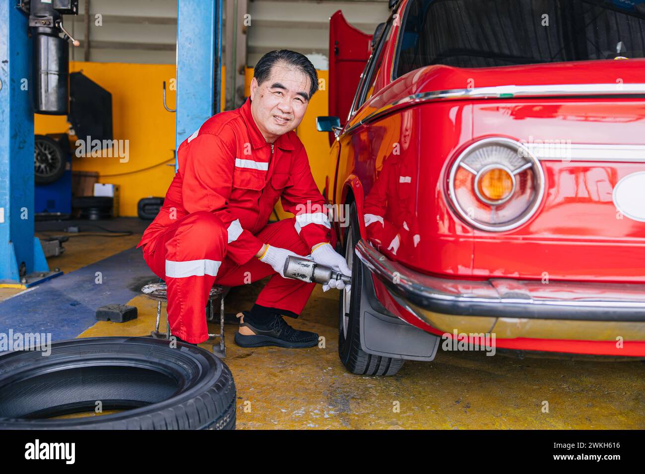 Senior professionista asiatico maschio meccanico officina lavoratore felice lavoro ruote pneumatici sostituzione servizio di manutenzione pneumatici auto Foto Stock