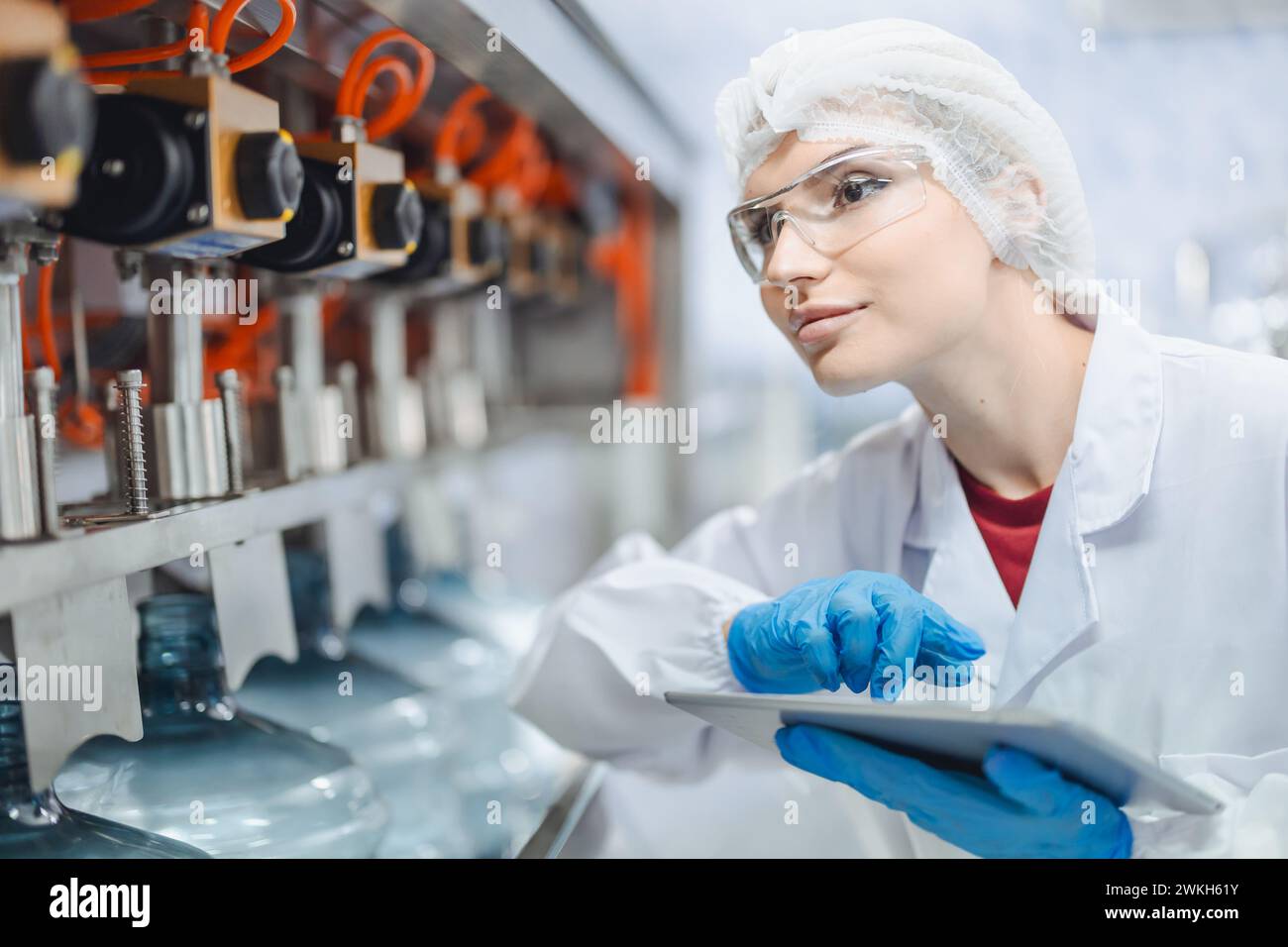 Le donne lavoratrici lavorano in fabbrica di acqua potabile controllare la qualità di controllo della macchina di rifornimento di acqua potabile funzionano Foto Stock