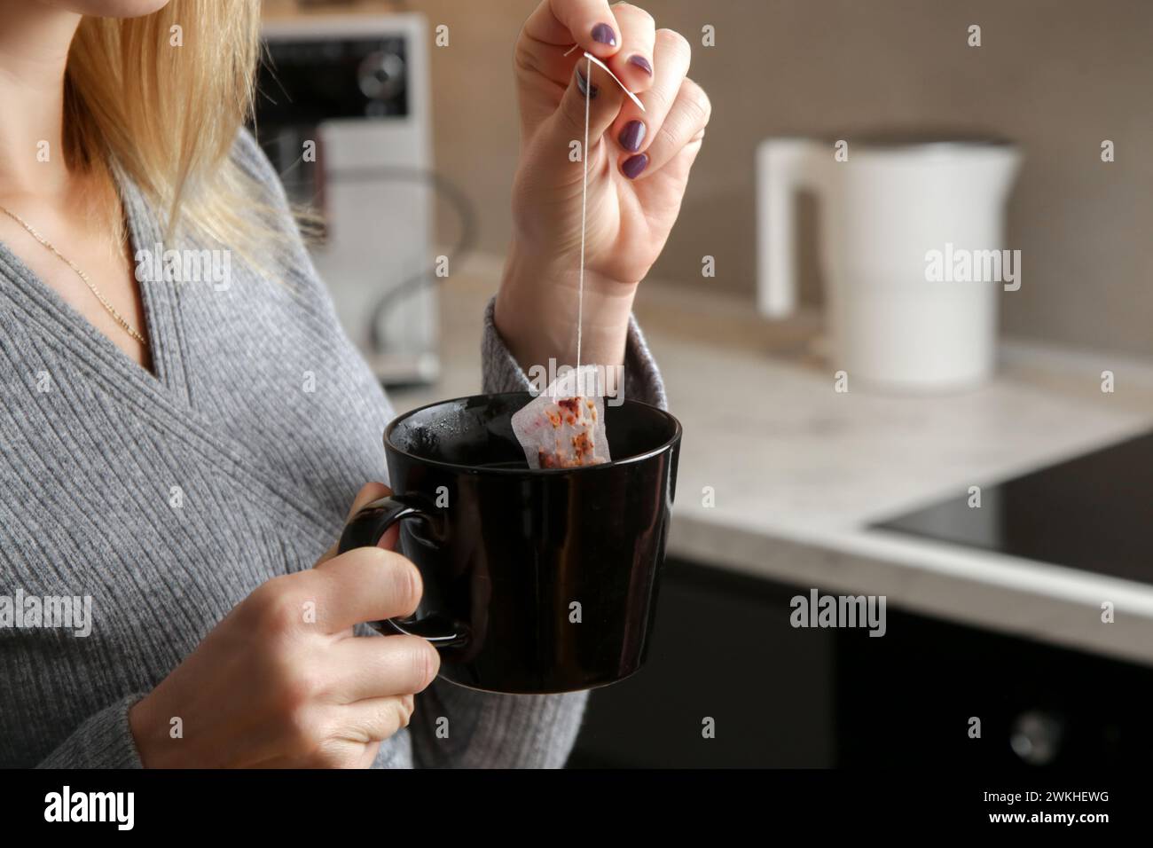 Giovane donna che prepara una tazza di tè in cucina Foto Stock