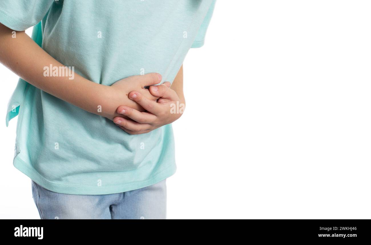 Un bambino tiene lo stomaco con le mani su uno sfondo bianco, primo piano. Dolore addominale nei bambini a causa di elminti, perdita di peso e cattiva salute. Co Foto Stock