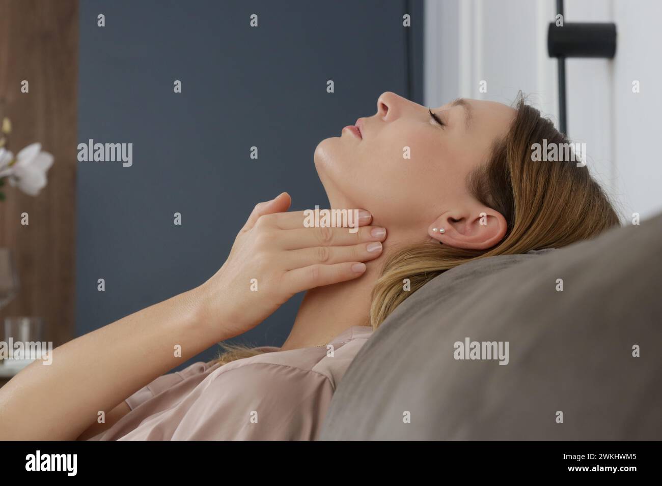 Donna caucasica che si tocca la gola. Mal di gola, raffreddore, influenza, tonsillite o problema della ghiandola tiroidea Foto Stock