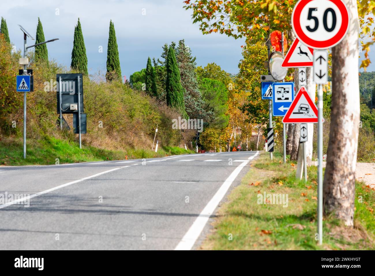 Strada asfaltata di campagna che attraversa la regione rurale della Toscana in autunno. Direzione del castello di Monteriggioni. Foto Stock