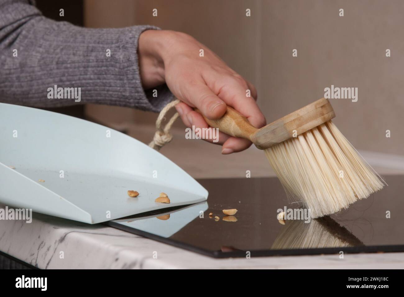 Immagine ravvicinata di un appartamento di donna che pulisce le mani con una scopa piccola e una padella Foto Stock