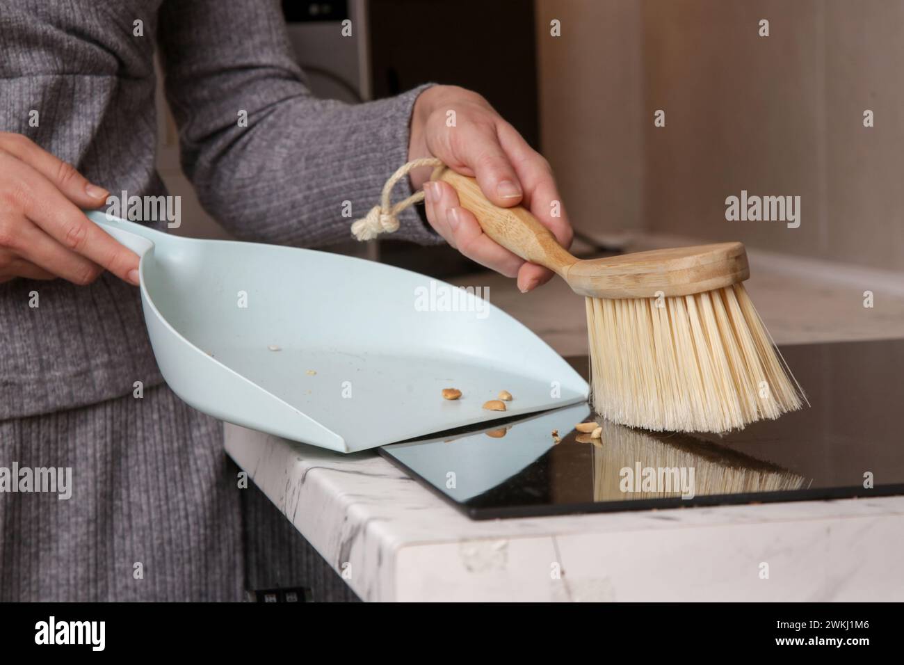 Immagine ravvicinata di un appartamento di donna che pulisce le mani con una scopa piccola e una padella Foto Stock