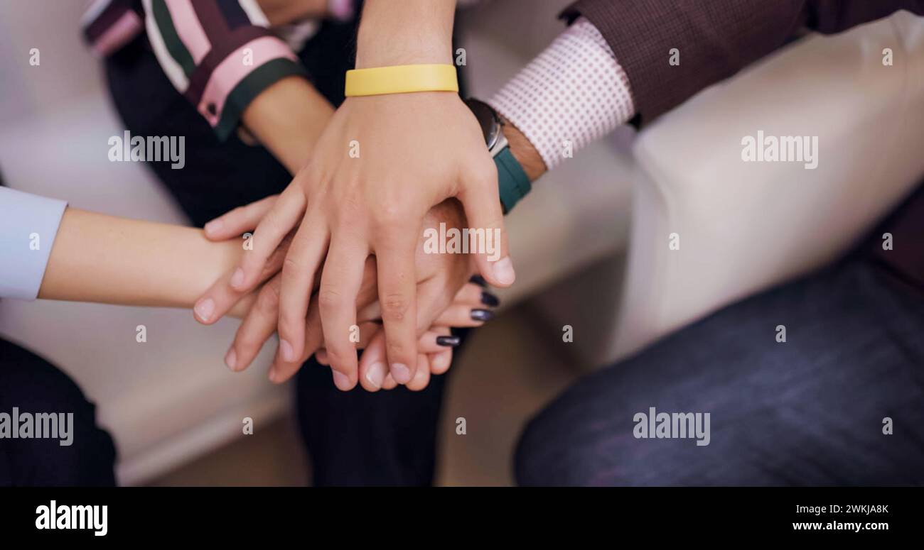 Un gruppo eterogeneo di individui si sta mettendo le mani l'una sopra l'altra, simboleggiando l'unità e la collaborazione del lavoro di squadra Foto Stock