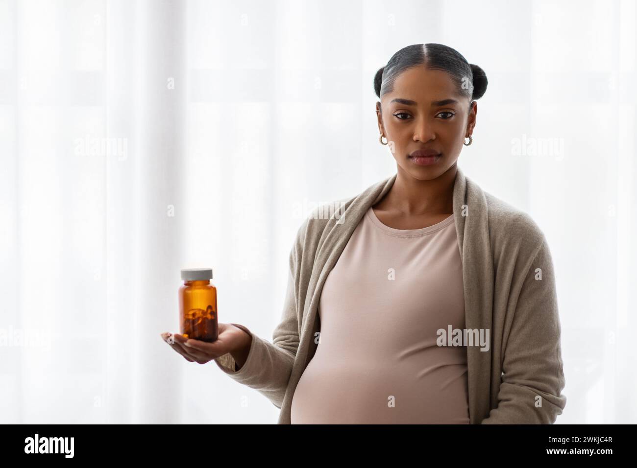 Donna nera gravida che mostra barattolo con la medicina Foto Stock