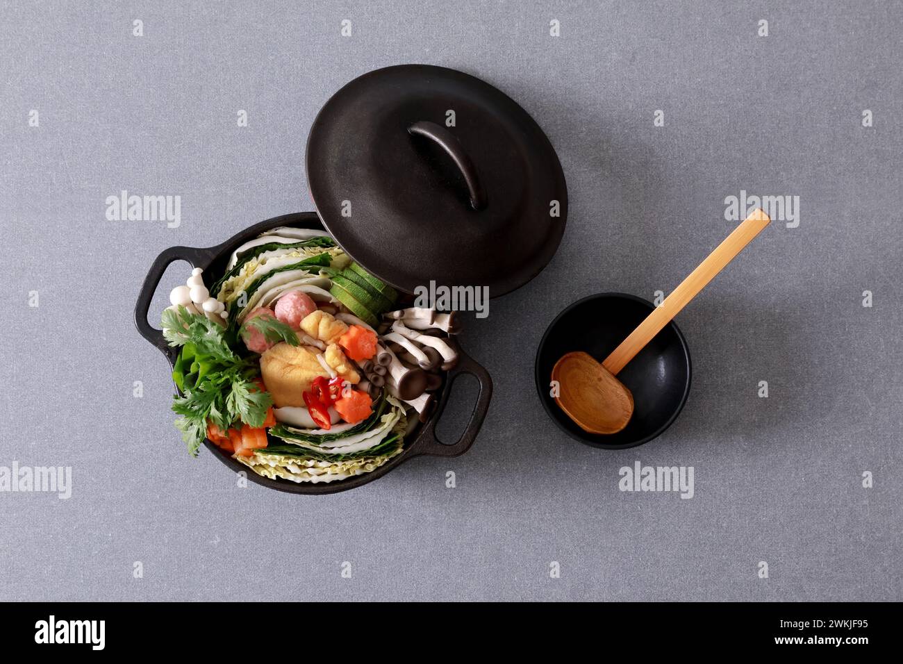 Pentola calda con verdure e funghi su sfondo grigio, vista dall'alto Foto Stock
