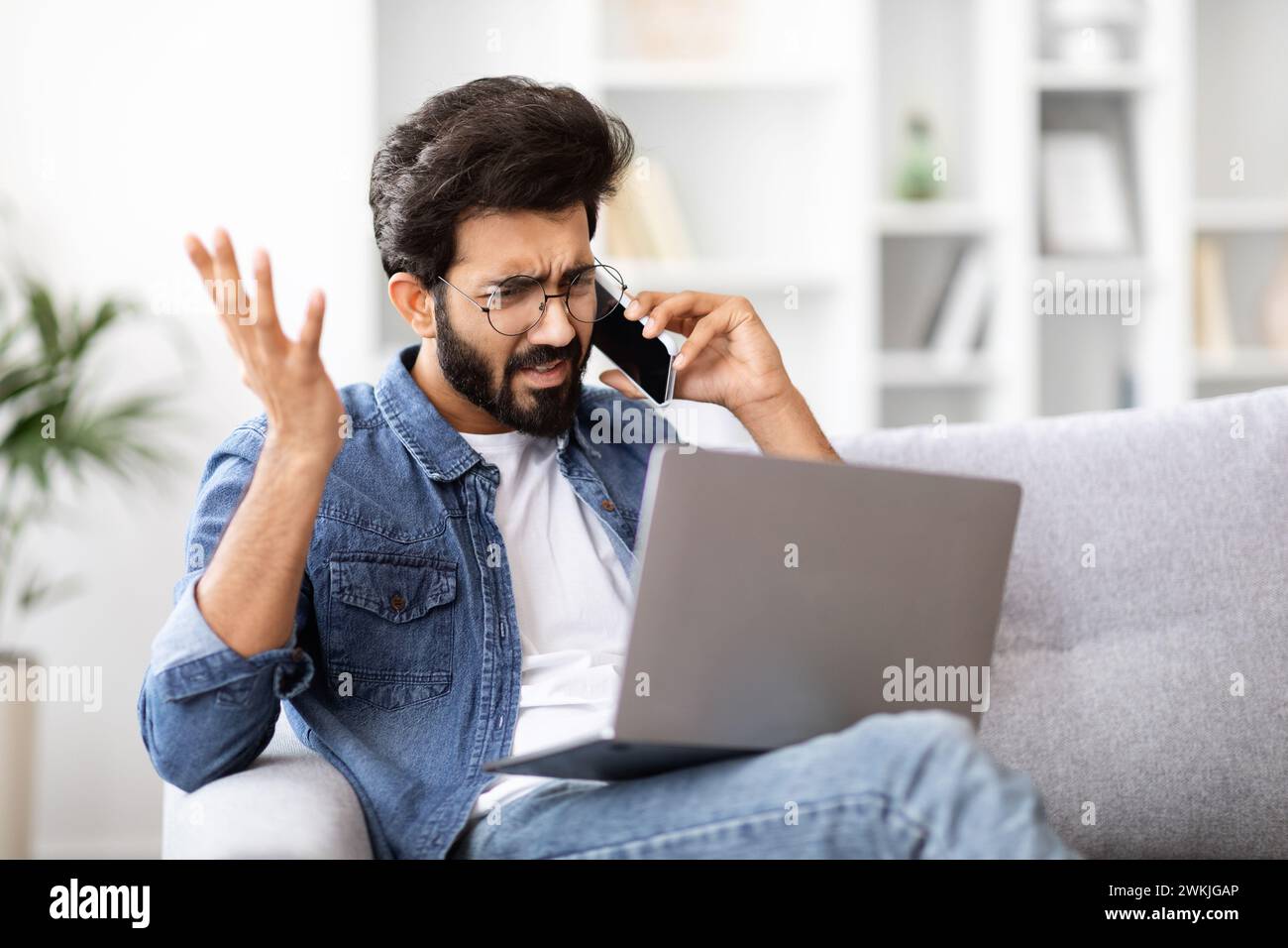 Infastidito indiano che faceva un gesto confuso durante una telefonata stressante a casa Foto Stock