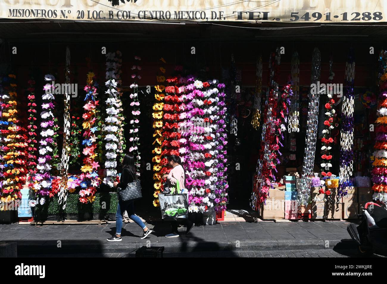 Passanti di fronte a un negozio di fiori artificiali nel centro storico, città del Messico Foto Stock