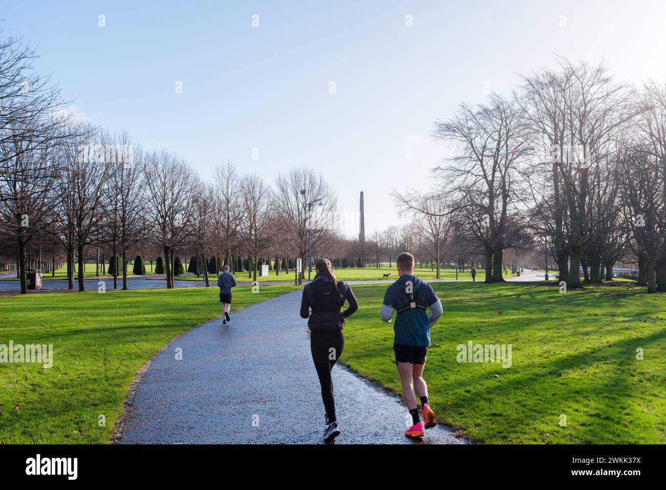 Glasgow Scozia: 12 febbraio 2024: Glasgow Green jogger (senza volti visibili) che si esercitano in una bella giornata invernale, con il Monumento di Glasgow Foto Stock