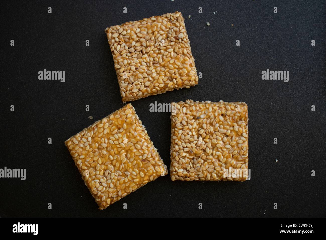 Til chikki su sfondo grigio nero. Il til chikki è un dolce indiano preparato con gesso e sesamo. Festa indiana makar sankranti dolce speciale Foto Stock