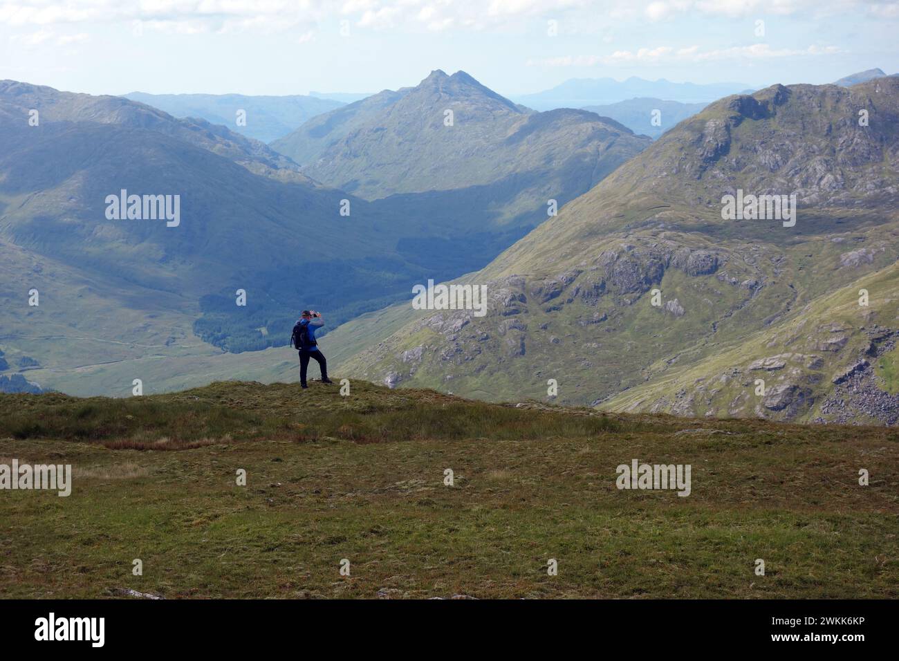Uomo (escursionista) che scatta foto di Glen Dessarry e del Corbett 'Bidean A' Chabair' dalle Highlands scozzesi di Corbett 'Fraoch Bheinn', Scozia, Regno Unito. Foto Stock