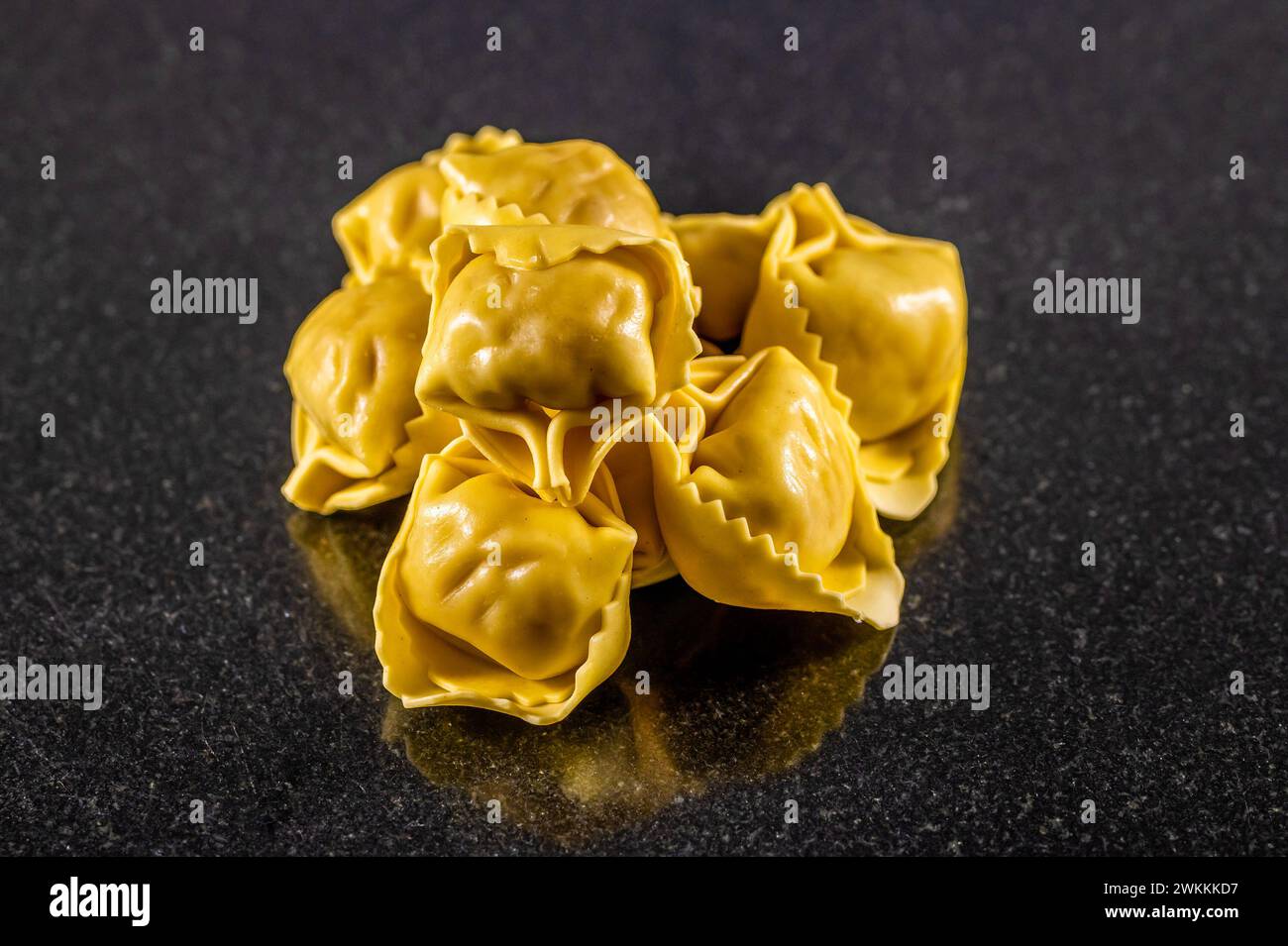 Vista ravvicinata dei pacchi di tortellini su un piatto di marmo scuro Foto Stock