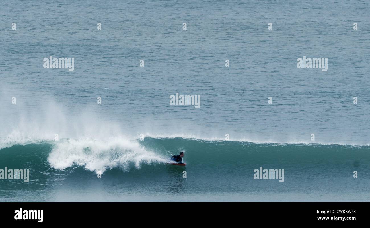 Surfista cavalca un'onda sdraiato sulla sua idea di surf oceano o sport acquatici a Western Cape, Sud Africa Foto Stock