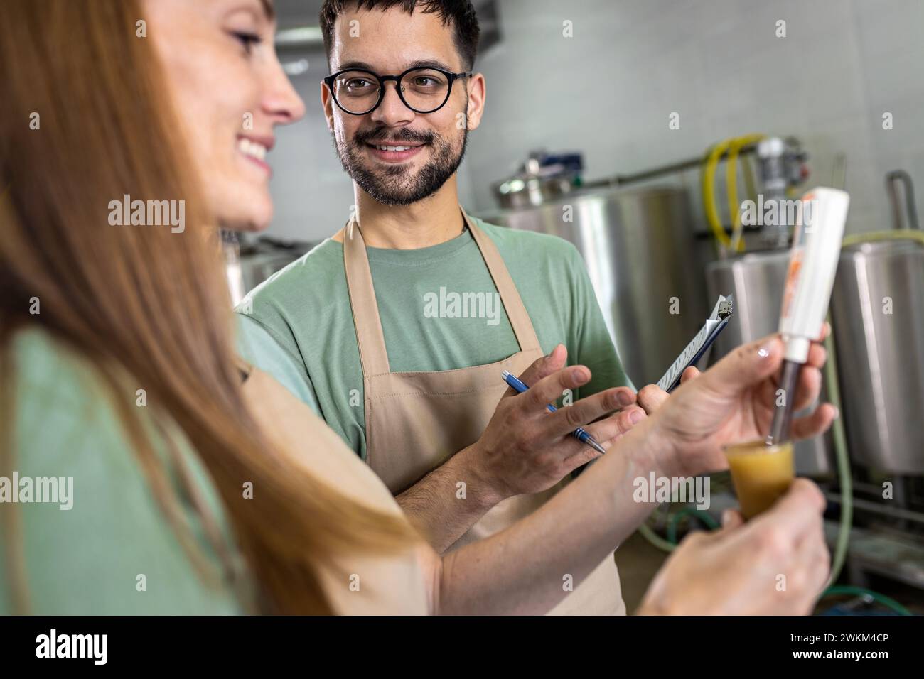 Uomo e donna che lavorano in birrificio artigianale che controllano il valore del pH della birra. Foto Stock