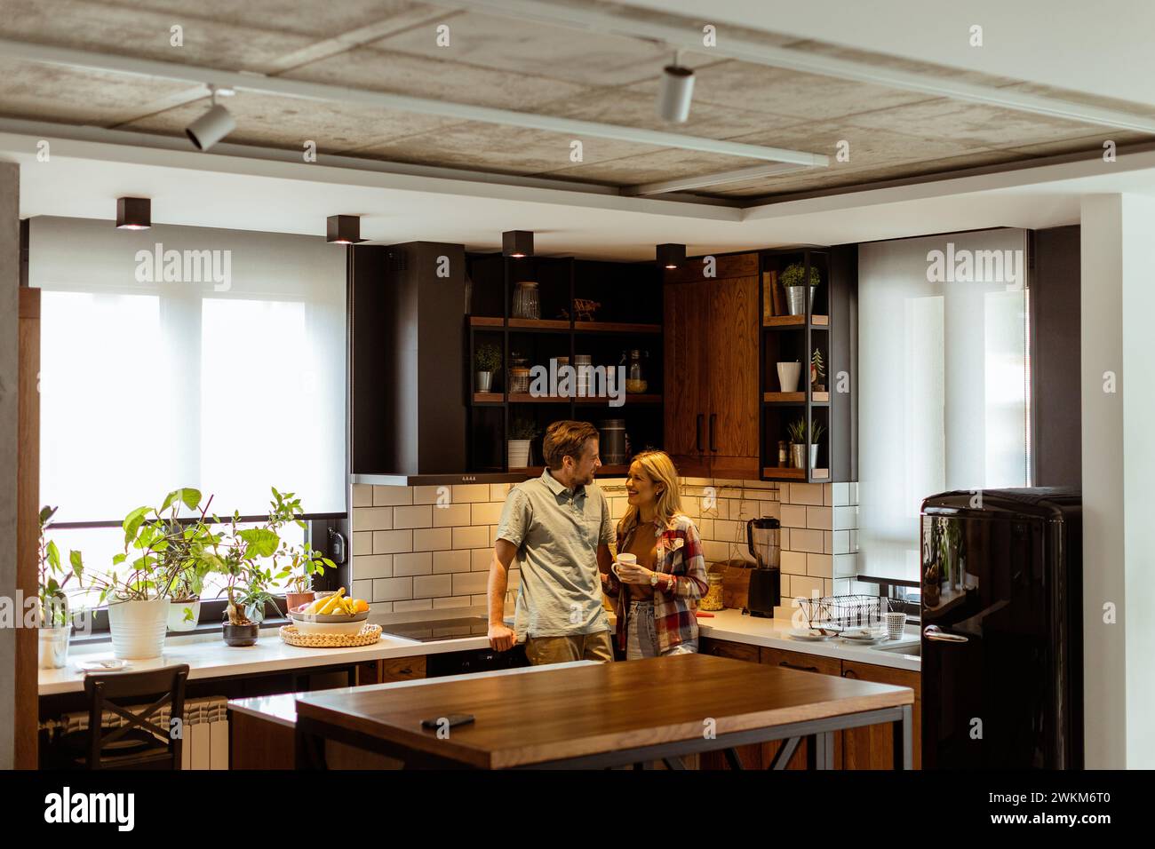 Una scena emozionante si svolge in una cucina domestica mentre una coppia condivide un affettuoso abbraccio, circondato dalla tranquillità della propria casa alla fine di Foto Stock