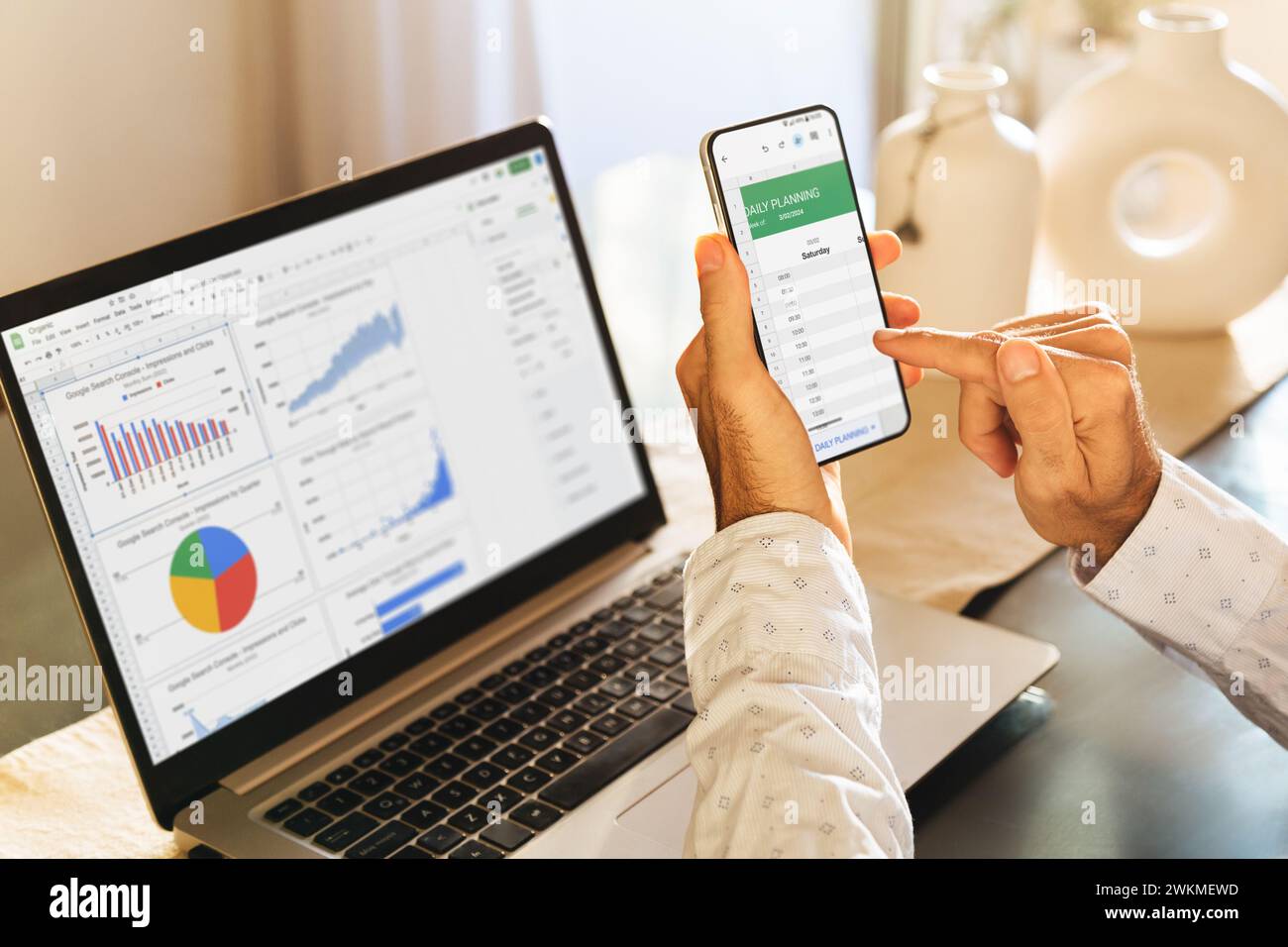 Uomo che utilizza l'app fogli su un telefono cellulare e un computer portatile. Google Workspace, strumenti di produttività digitale online. ROSARIO, ARGENTINA - 20 FEBBRAIO 2024. Foto Stock