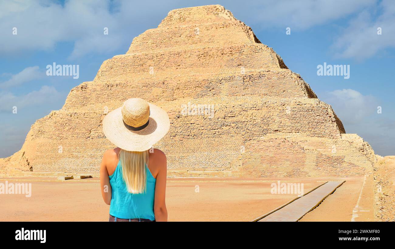 Saqqara, Egitto; 11 novembre 2023 - Una donna dai capelli biondi si trova di fronte alla piramide a gradini più antica dell'Egitto. Si trova a Saqqara Foto Stock